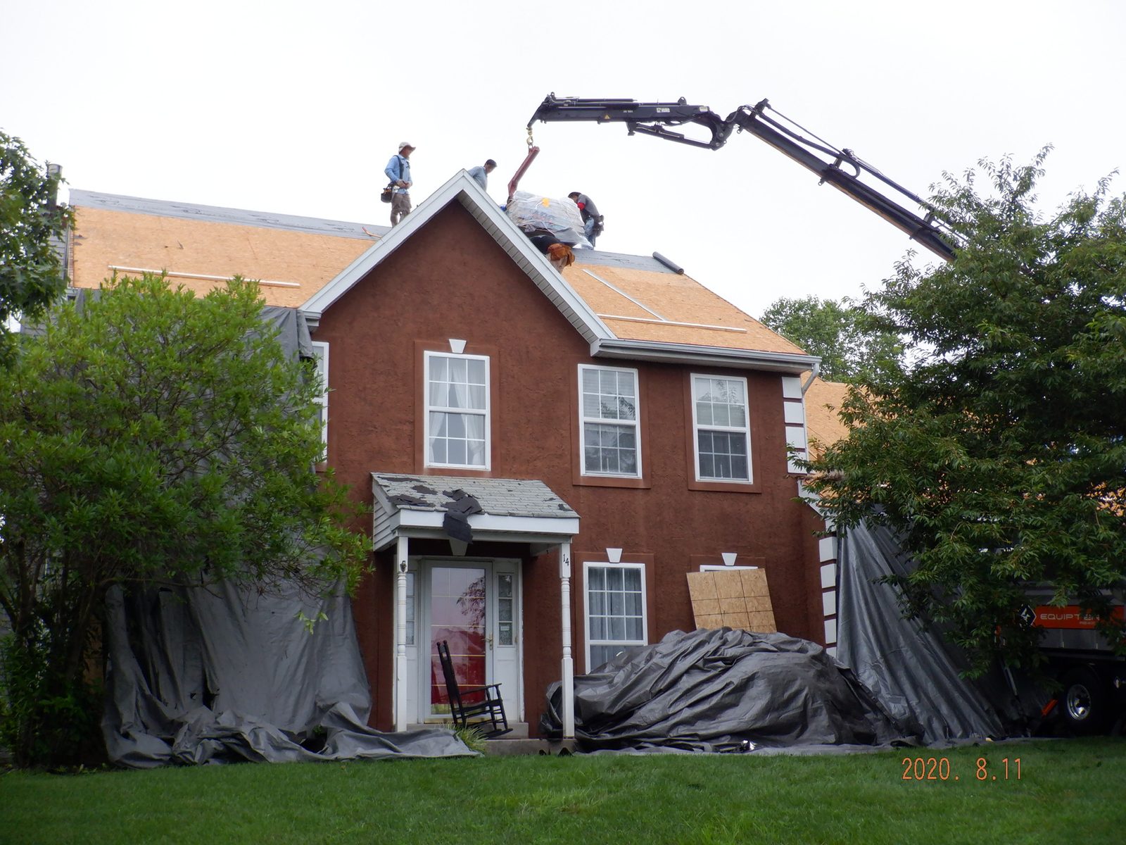 Crane loading shingle bundles onto the roof of a brick home in Wyomissing, PA